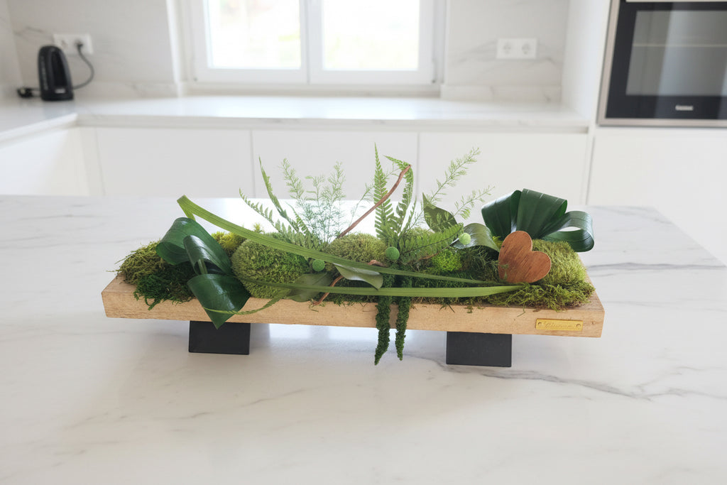 Composition végétale stabilisée artisanale sur plateau en bois, mousses naturelles, fougères et feuillages verts – centre de table moderne sans entretien