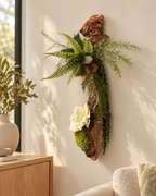 Décoration murale en bois de mopani avec fougères, mousses et feuillages stabilisés, ornée d’une fleur blanc crème\.