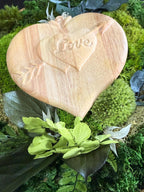 Centre de table végétal en bois de manguier avec cœur gravé love, composition en mousse stabilisée et feuillage naturel